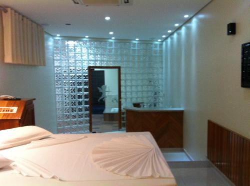 a room with a bed and a glass wall at Status Motel Ourinhos in Ourinhos