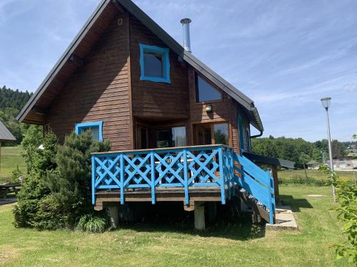 une petite maison avec un porche bleu dans une cour dans l'établissement Chalet nordique 214, à La Féclaz