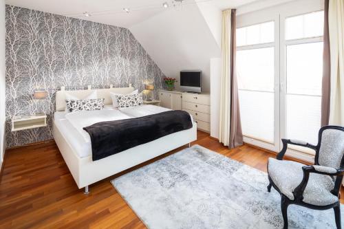a bedroom with a white bed and a chair at Ferienloft Inselliebe in Norderney