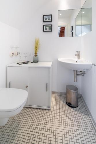 a white bathroom with a toilet and a sink at Ferienloft Inselliebe in Norderney