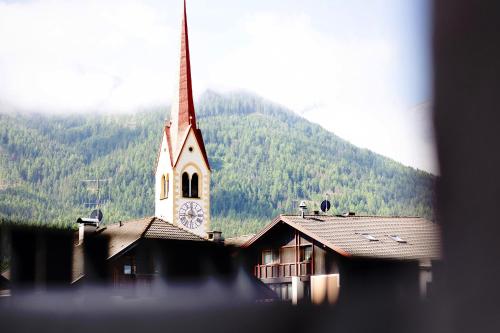 a church with a clock tower in front of a mountain at Kriendl Nr 4 in Valdaora