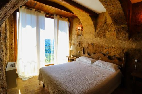 a bedroom with a bed and a large window at La Cava - Palazzo Pallotti in Bagnoregio