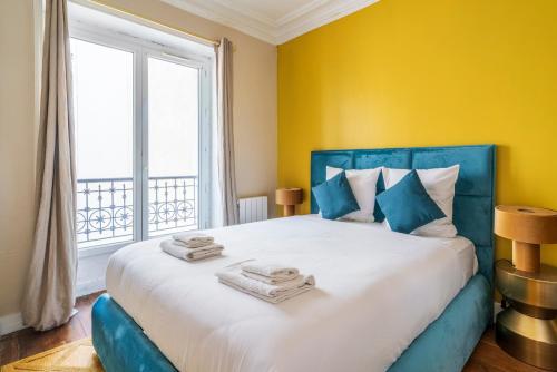 - une chambre avec un grand lit aux murs jaunes et une fenêtre dans l'établissement Appartement au cœur de Paris Montparnasse, à Paris