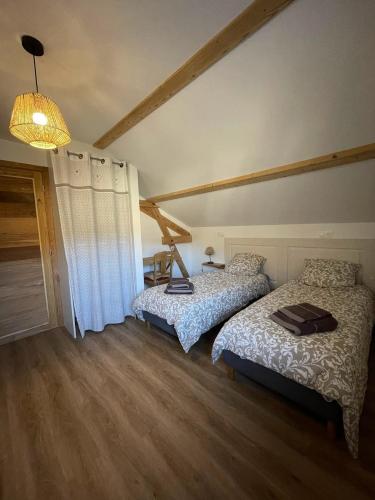 une chambre avec deux lits et un lustre dans l'établissement Gîte 5 personnes, à Le Bonhomme