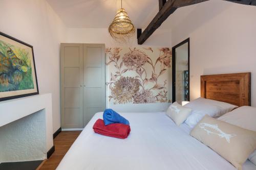 un lit blanc avec un chapeau rouge et bleu dessus dans l'établissement Dans les Airs, à Quimper