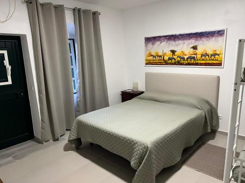 a bedroom with a bed and a painting on the wall at Herdade da Moringa in Corte do Pinto