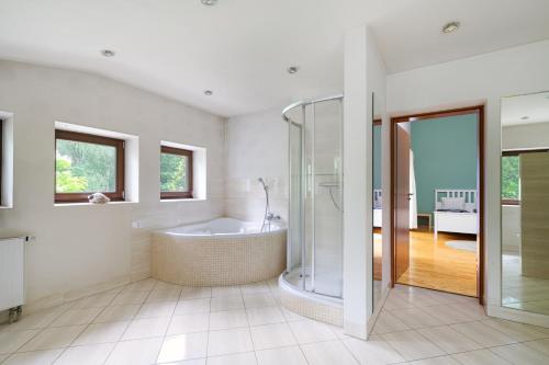ein weißes Badezimmer mit Badewanne und Dusche in der Unterkunft Chill&SPA Villa 30 min od Warszawy, Jacuzzi, Sauna, Sport in Konstancin-Jeziorna
