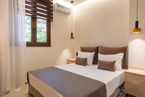 a bedroom with a bed with white sheets and a window at Irisma Luxury Villa with private pool in Archanes