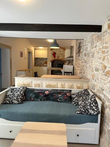 een bed in een kamer met een stenen muur bij Apartment By the Sea in Milna