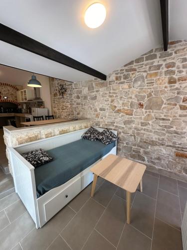 een bed in een kamer met een bakstenen muur bij Apartment By the Sea in Milna
