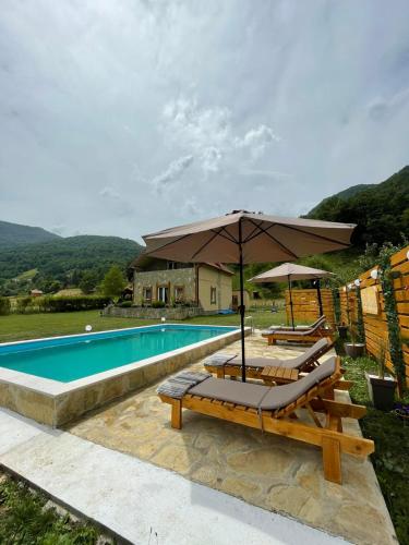 a pool with two lounge chairs and an umbrella at Vila Kristina in Andrijevica