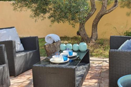 a table with cups and plates on it on a patio at Villa Pierre Blanche le calme a 5mn du centre ville in Nîmes