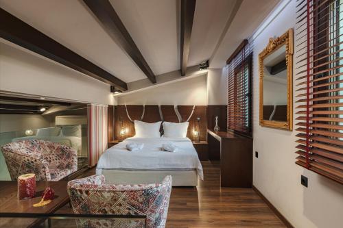 a hotel room with a bed and two chairs at Vintage Suites Trikala in Tríkala