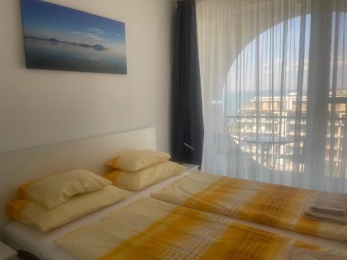 a bed with two pillows in a bedroom with a window at Vízparti Apartman in Siófok