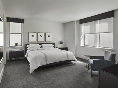 a bedroom with a bed and a chair and windows at AKA Central Park in New York