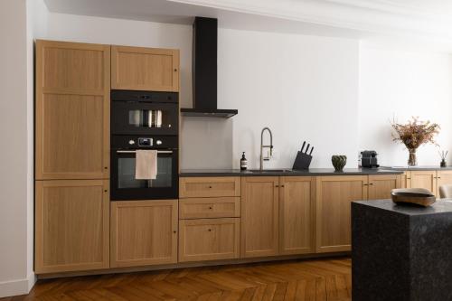 La cuisine est équipée d'armoires en bois et d'un four noir. dans l'établissement Champs Élysées Montaigne Luxury 2 bedroom, à Paris