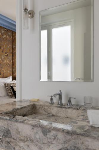La salle de bains est pourvue d'un lavabo en marbre et d'un miroir. dans l'établissement Champs Élysées Montaigne Luxury 2 bedroom, à Paris