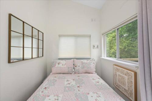 ein Schlafzimmer mit einem Bett mit rosa Kissen und einem Fenster in der Unterkunft Dream Cottage in Lewes in Lewes