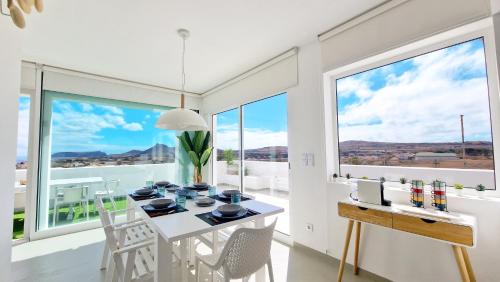 a dining room with a table with chairs and large windows at Casa do Pico by Casas dos Lebre in Porto Santo