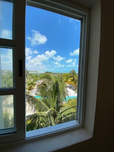 a window with a view of a beach and palm trees at La Casa del Sol Beachfront in El Cuyo