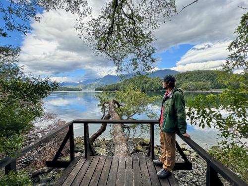 a man standing on a wooden bridge near a lake at Puyuhuapi Lodge & Spa in Puerto Puyuhuapi