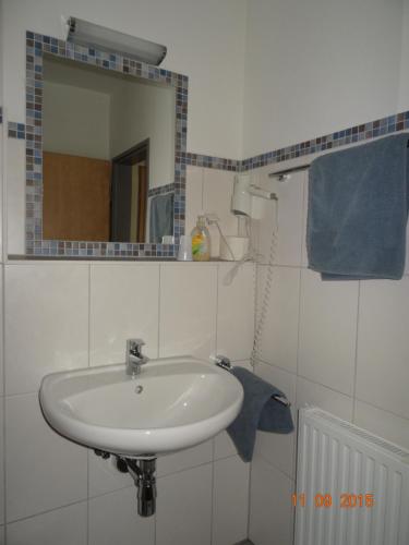 a bathroom with a sink and a mirror and blue towels at Pension Alram Hof in Eggenfelden