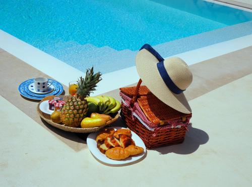 a plate of fruit and a hat next to a pool at Aoni Suites in Aegina Town