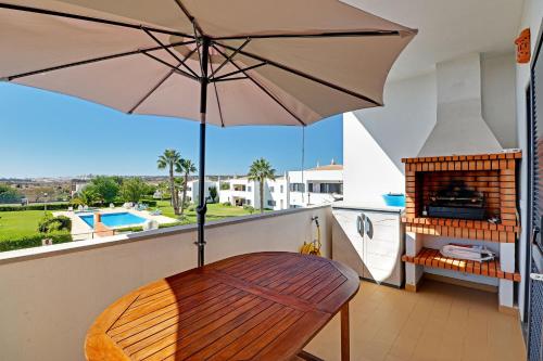 a balcony with a wooden chair and an umbrella at Pêra Secret Garden 1 and Pool by Homing in Pêra