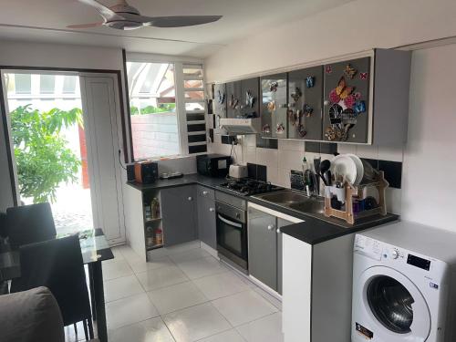 a kitchen with a stove and a washing machine at Gîte le Petit Manguier in Les Abymes