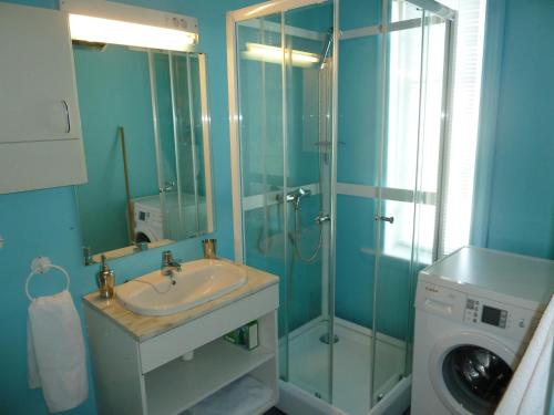 a bathroom with a shower and a sink and a washing machine at Red Old House Tromsø Apartment in Tromsø