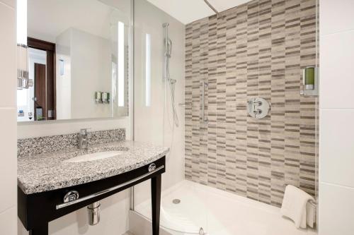 a bathroom with a sink and a shower at Hampton By Hilton London Stansted Airport in Stansted Mountfitchet