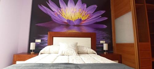 a bedroom with a painting of a purple flower on the wall at Reivi Vilanova de Arousa in Villanueva de Arosa