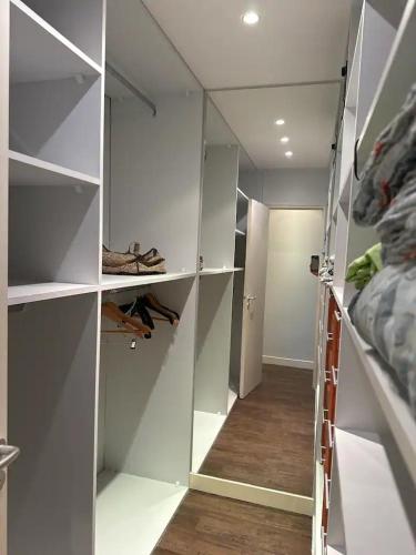 un placard vide avec des étagères blanches et un couloir dans l'établissement Cocon contemporain et confortable proche Paris, à Alfortville