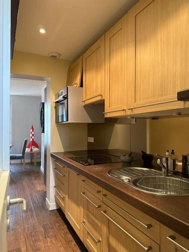 une cuisine avec des armoires en bois et un comptoir dans l'établissement Cocon contemporain et confortable proche Paris, à Alfortville