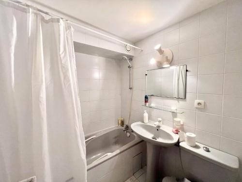 une salle de bain blanche avec un lavabo et une baignoire dans l'établissement Logement avec accès direct à la mer à La Tranche-sur-Mer, à La Tranche-sur-Mer