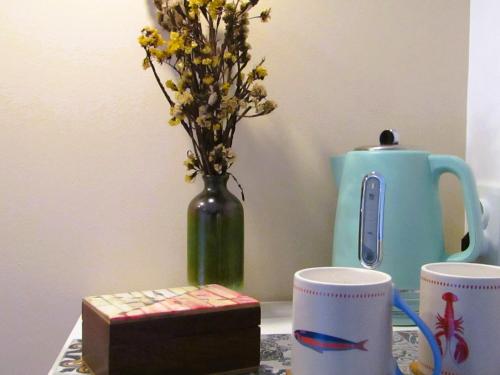 a table with two cups and a vase with flowers at A-Típica GuestHouse in Ponta Delgada