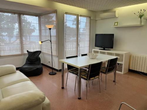 ein Wohnzimmer mit Tisch und Stühlen und einem Fernseher in der Unterkunft ALQUILER PISO BLANES con VISTAS AL MAR in Blanes