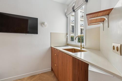 Il comprend une cuisine avec un évier et une télévision murale. dans l'établissement Cosy studette - Invalides - 1pers, à Paris