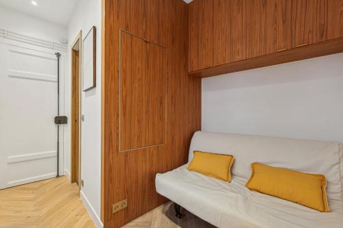 - un canapé blanc avec des oreillers jaunes dans l'établissement Cosy studette - Invalides - 1pers, à Paris