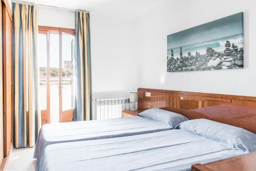 a bedroom with two beds and a large window at Apartamentos Balear Beach in Palmanova