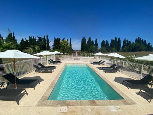 une piscine avec chaises et parasols dans l'établissement Domaine Font Castel - Gîte Wavre, à Béziers