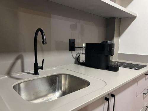 a kitchen counter with a sink and a coffee maker at Loft de Luxo "Novo" no Coração de Blumenau a 10min a Pé da Vila Germânica in Blumenau