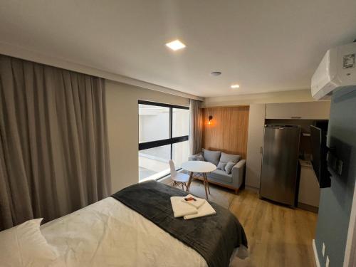 a hotel room with a bed and a living room at Loft de Luxo "Novo" no Coração de Blumenau a 10min a Pé da Vila Germânica in Blumenau