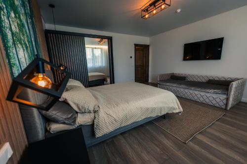 a bedroom with a bed and a couch and a television at Paežerės istorijos, Druskininkai in Veršiai