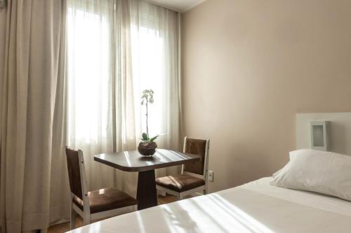 a bedroom with a table and a bed and a window at Plaza São Rafael Hotel in Porto Alegre