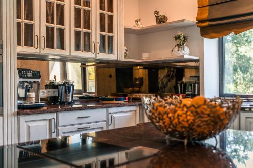 a kitchen with white cabinets and a bowl of fruit on a counter at Paežerės istorijos, Druskininkai in Veršiai