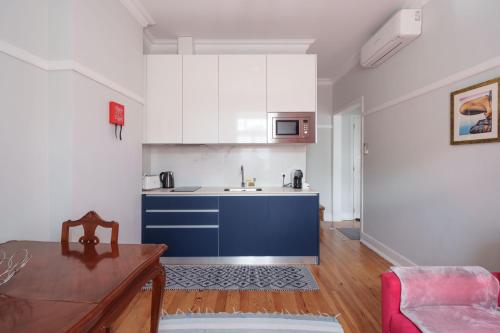 a kitchen with blue and white cabinets and a table at Apartamentos T1 de charme - Pombal, Centro Histórico in Pombal
