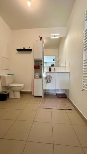 La salle de bains est pourvue d'un réfrigérateur blanc et de toilettes. dans l'établissement Grand studio cosy, à Noisy-le-Grand