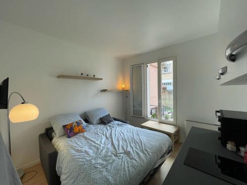 une chambre avec un lit, un bureau et une fenêtre dans l'établissement Studio cosy à 20 min de Paris, à Bois-Colombes