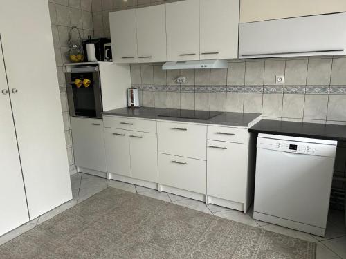 - une cuisine blanche avec des placards blancs et un lave-vaisselle dans l'établissement Coccinelle, à Montataire